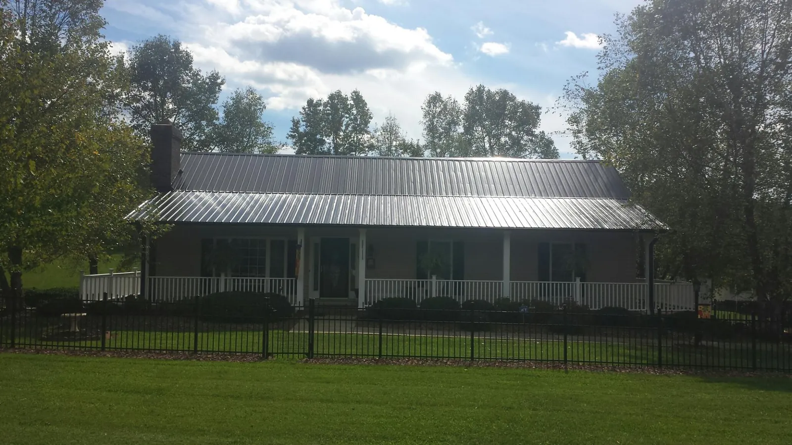 Gray metal roof on a brick ranch with a full width front porch — Gutter Guard Installation work by our crew in Sligo