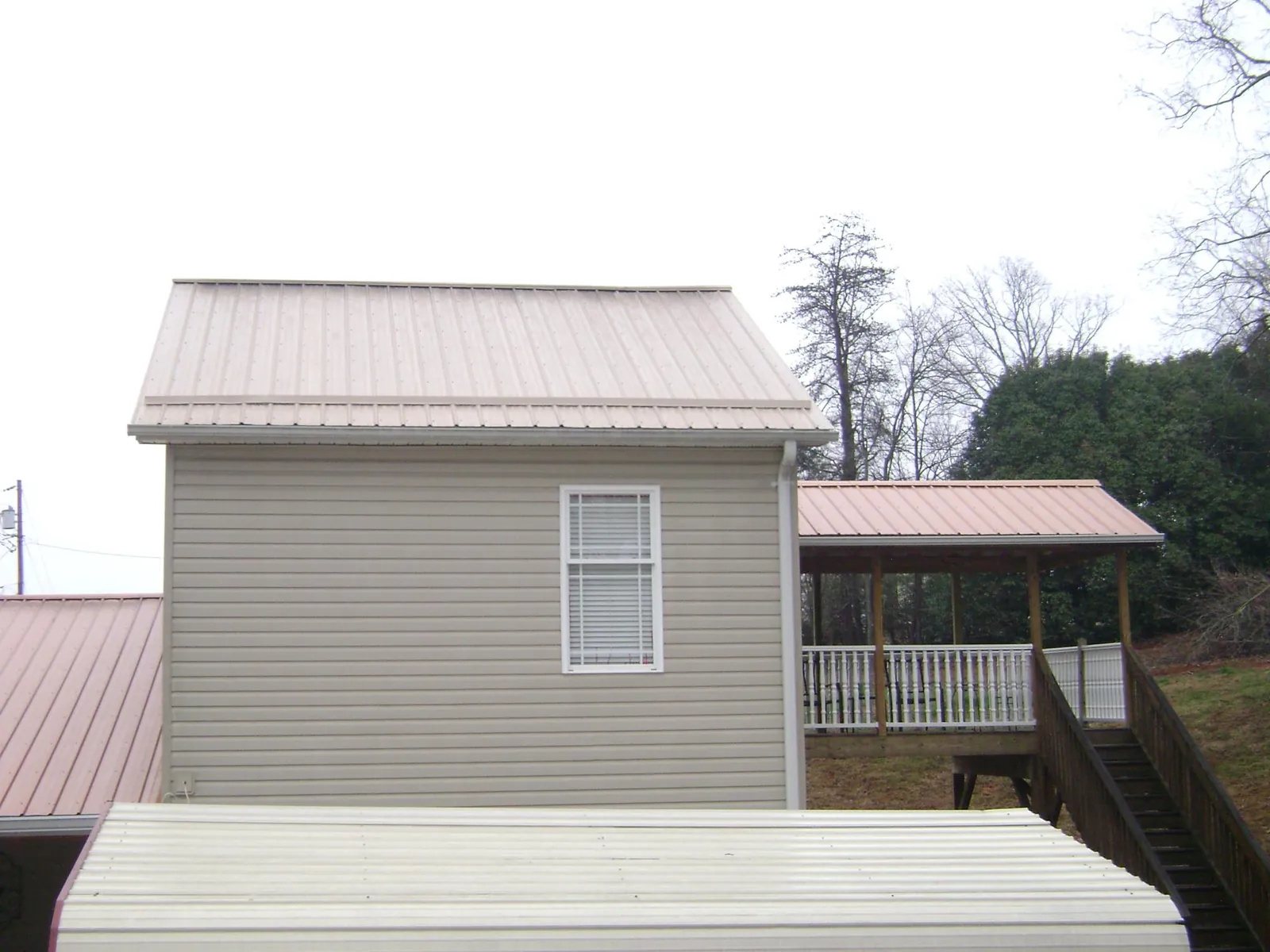 Tan metal roofs on a two story addition and attached porch, from a Roof Replacement job in Sligo