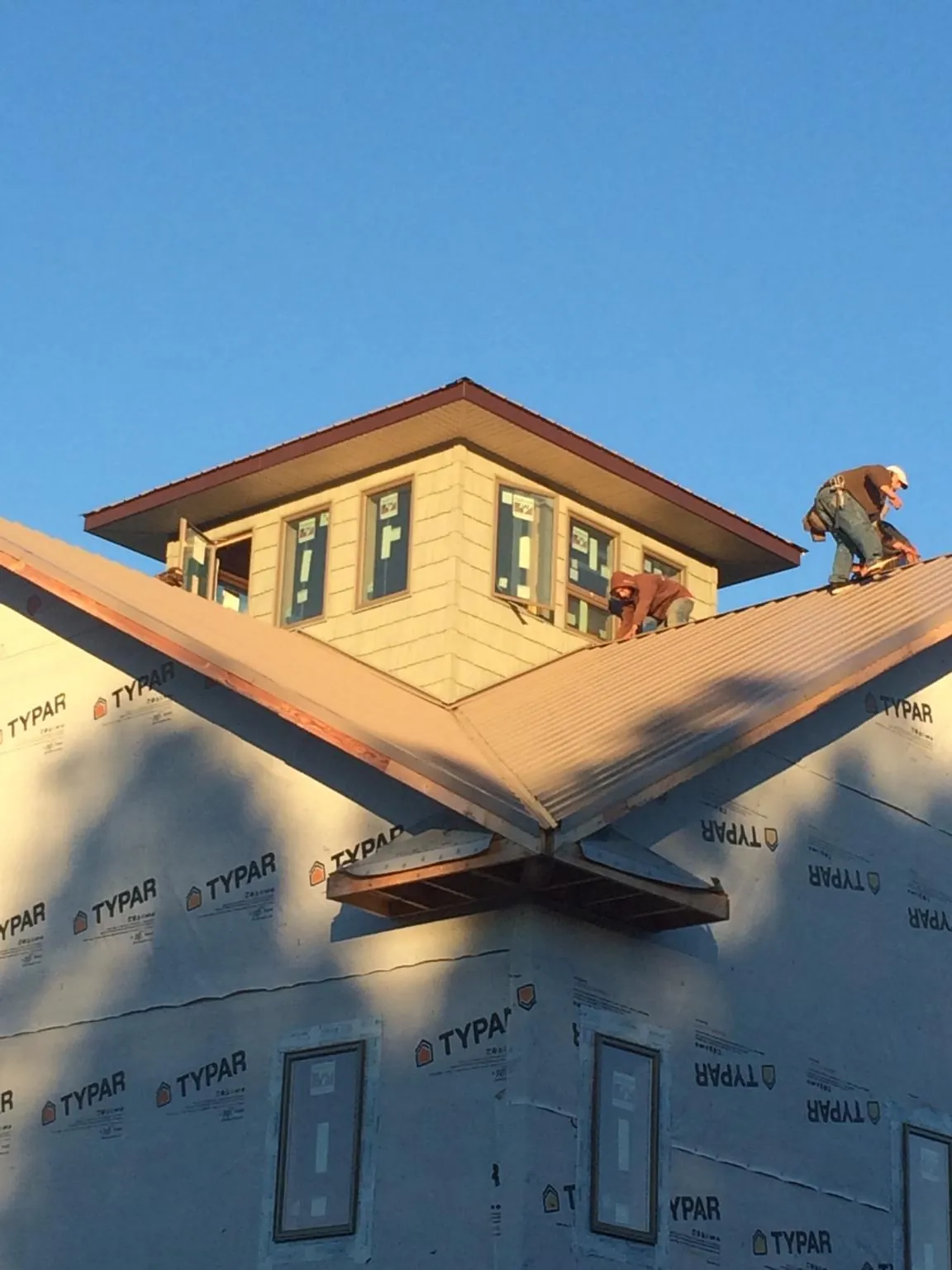 Roofers working around a rooftop cupola on a new metal roof at sunset — Roof Waterproofing in Sligo by Roofing Brothers